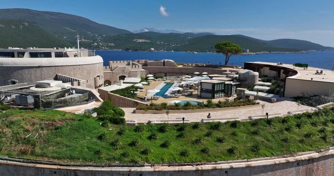 Aerial zoom-out of Mamula Island resort surrounded by clear sea and sunshine.