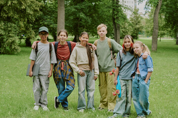 Group of diverse teenagers standing together in park, smiling and posing for camera, multiethnic...