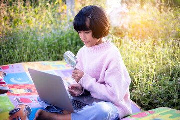 Cute little girl is using the smart phone. grass on background. On girl a hairpin with a pumpkin