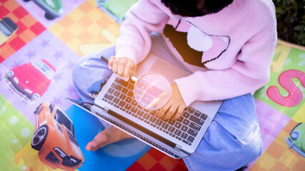 Cute little girl is using the smart phone. grass on background. On girl a hairpin with a pumpkin