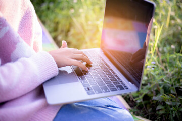 Cute little girl is using the smart phone. grass on background. On girl a hairpin with a pumpkin