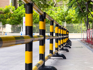 Urban sidewalk barrier made of black and yellow metal pipes used for pedestrian guidance and safety...