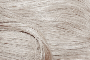 Blond hair close-up as a background. Women's long blonde hair. Beautifully styled wavy shiny curls....