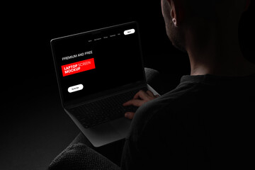 Person in an office working on a laptop at a desk with a computer monitor