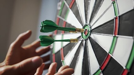 Close Up of Dartboard with Two Green Darts Hitting Bullseye with Hand Near By Highlighting Accuracy and Success in a Blurred Background