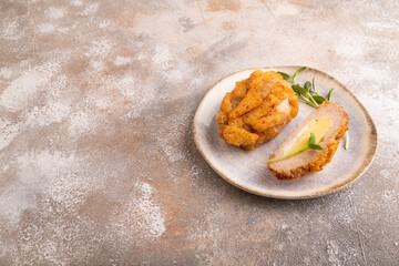 Chicken schnitzel on blue plate with microgreen on brown concrete. Diet, healthy eating. side view, copy space