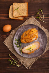 Chicken Schnitzel on gray plate with microgreen on brown wooden background and linen textile. top view, close up