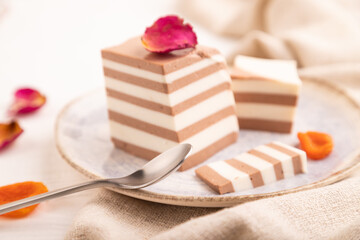 Cocoa and milk jelly with dried apricots on white wooden background, side view, selective focus