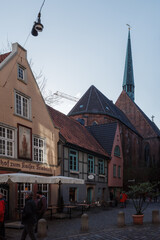 Obraz premium A street scene in the historic Schnoor Quarter (Schnoorviertel) of Bremen, Germany, with the St. Johann Church in the background.
