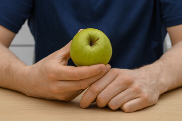 A man holding and eating a green apple