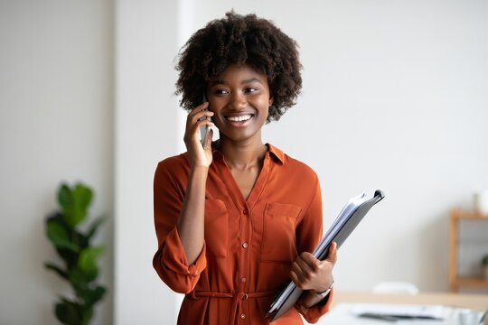 Professional african american woman talking on phone holding clip board in office space