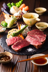【黒毛和牛ステーキ】レアで美しく焼き上げた黒毛和牛モモ肉のステーキ。ジューシーな肉の旨みを引き立てるのは、素揚げした季節の野菜と彩り豊かな薬味。わさびや塩、日本酒とともに、和の美味を贅沢に味わう一皿です。