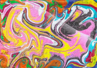 Abstract ebru background. Bright iridescences of paint on the water. A creative artistic background for graphic design. Yellow pink blue and black shades. The fluid texture of colors. Contemporary art