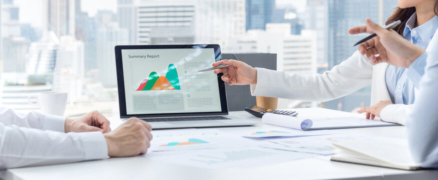 Business team analyzing summary report data on laptop in modern office meeting