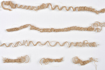 This close-up, top-down studio shot features several strands of natural jute twine artfully...