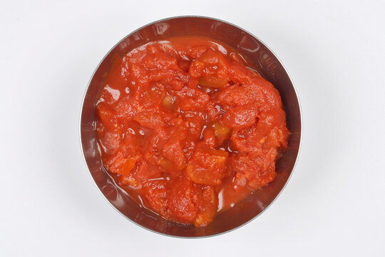 Close-up, top-down studio shot features a metal bowl filled with rich, chunky crushed tomatoes, perfect for cooking delicious meals