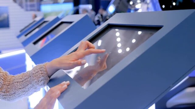 Woman interacting with a touchscreen kiosk in a modern, bright environment with multiple kiosks lined up
