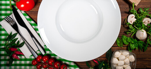 Round plate decorated with tomatoes, mushrooms, spinach, basil and spices. Dish on a white square...