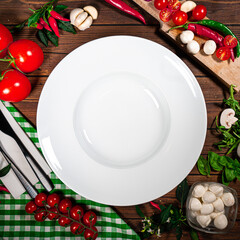 Round plate decorated with tomatoes, mushrooms, spinach, basil and spices. Dish on a white square...