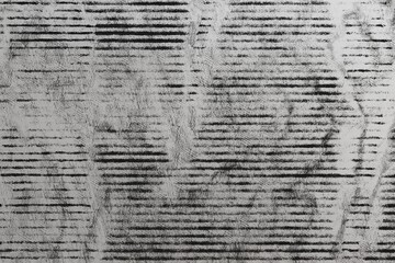 Obraz premium A grayscale abstract artwork featuring dense, horizontal lines in varying thicknesses and opacities, creating a textured, layered effect reminiscent of aged newspaper print or a distressed surface. 
