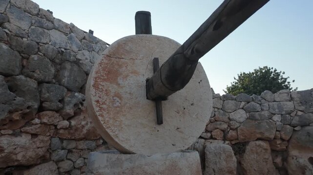 Close-up shot of a historical millstone or olive press at the Kanlıdivane (Kanytelleis) ancient city in Mersin, Turkey. Detail of the ancient agricultural mechanism at an archaeological site.
