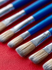 Fototapeta premium A bunch of paint brushes sitting on top of a red surface
