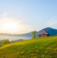 small wooden house on green mountain valley  at the early morning
