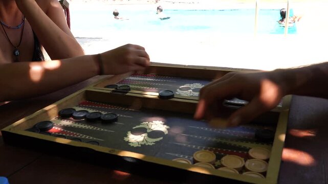 Close-up on a Backgammon Game with People Relaxing by the Swimming Pool