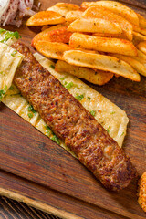Traditional Adana kebab with fries, lavash, bulgur and onion salad
