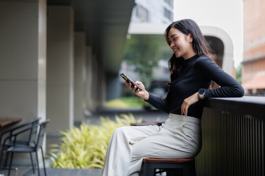 Young businesswoman using smartphone while relaxing outdoors