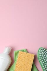Vertical photo with cleaning products including bottle, sponge, spray on pink background. Flat lay...