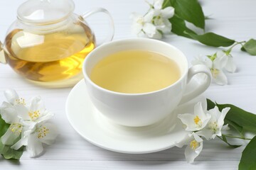 Brewed green tea with jasmine in cup and teapot on white background