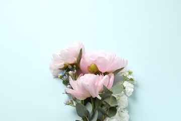 Beautiful bouquet of flowers and pink peonies on blue background, top view, space for text