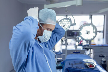 Overhead surgical lights illuminating covered instrument table, with instrument trays near window