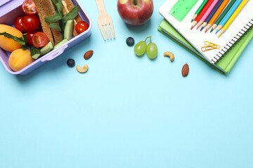 The lunchbox features delectable sandwiches and fresh snacks on a pastel blue background, offering...