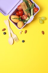 Vertical photo of lunchbox with healthy snacks and fruits placed on desk