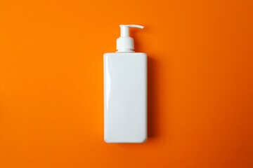 SPF skin care concept. White sunscreen bottle on orange surface