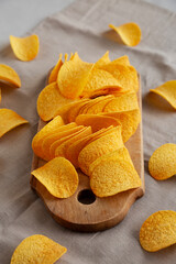Bacon flavoured potato chips on a wooden board, side view.