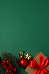 Top vertical view of gift box tied and Christmas decorations on green background 