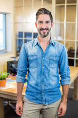 Fototapeta premium Man standing at wooden desk in modern office with plant, scattered papers and glass partition