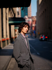 Portrait of handsome Chinese young man wearing gray suit posing in the street, young guy with black...