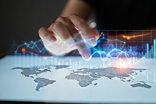 A hand interacting with a digital world map and financial data on a glowing screen display surface