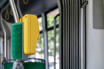 Vivid yellow stop request button and green upholstered safety pole inside a modern public transit...