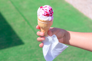 Handheld ice cream cone with a vibrant berry swirl. Refreshing ice cream cone, perfect for a sunny...