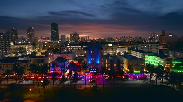 Aerial view of Ocean Drive, sparkling in vivid neon colors under the twilight sky, creating a vibrant contrast against the darker buildings, Miami Beach, Florida, United States.