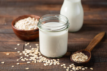 Oat milk in glass jar on wooden table. Lactose free dairy free alternative milk product, homemade oat milk