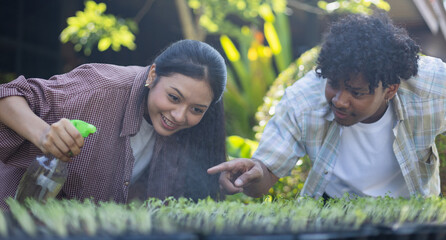 Young scientist in farm agricultural research team working together to nurture seedlings and study...
