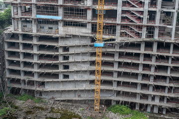 Unfinished floors of a multi-storey building without external walls. Fragment of the facade of a monolithic residential building under construction with crane