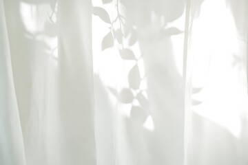Soft sunlight filtering through sheer curtains with leaf shadows