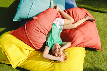 Child laughing on colorful cushions outdoors
